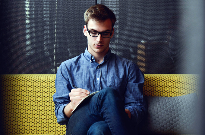 Man writing ideas down in notepad.