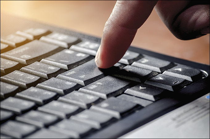 Image: Finger poised on Enter key on laptop.